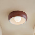 Red Clérachic ceiling light with a textured terracotta-red outer bowl and a white inner rim around a lit round bulb.
