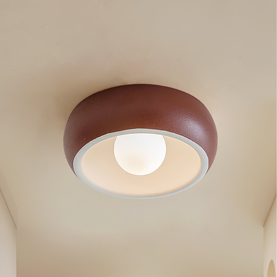 Red Clérachic ceiling light with a textured terracotta-red outer bowl and a white inner rim around a lit round bulb.