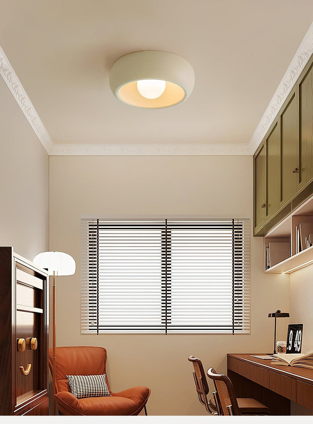 Beige Clérachic ceiling light in a small study with white mouldings, an orange armchair, a desk and green wall cabinets.