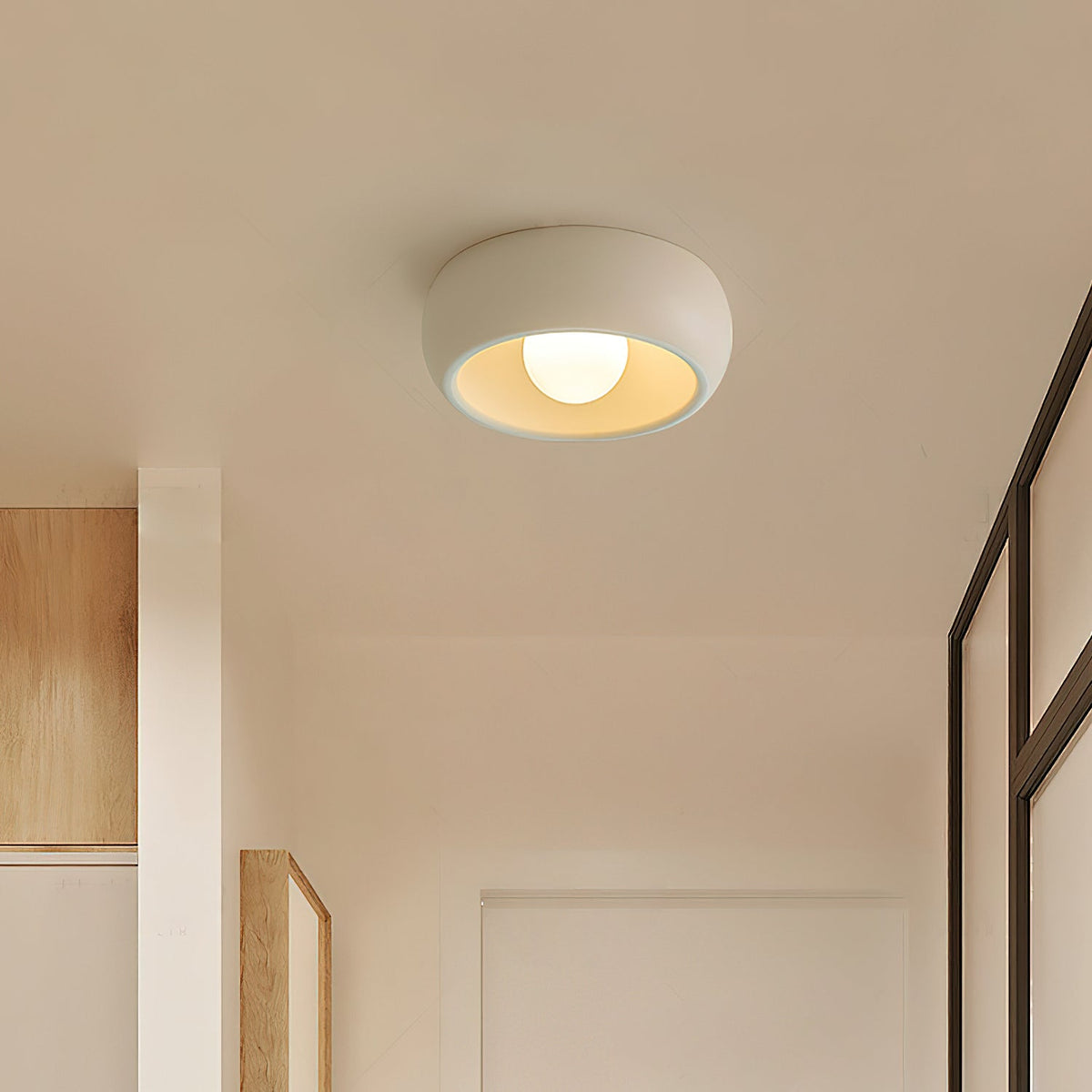 Beige Clérachic ceiling light in a narrow passage with pale wood panelling and a dark-framed glass door at the side.