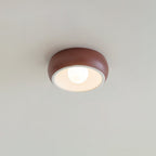 Red Clérachic ceiling light on a pale ceiling, a terracotta-red outer bowl around a white inner rim and a round bulb.