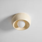 Angled view of this cream Clérachic ceiling light, its round white bulb deep inside the soft-edged bowl on a pale surface.