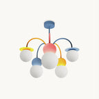 A Clérachic chandelier on a plain white backdrop, with a blue ceiling plate, pink centre and five white globes on yellow, orange and blue arms.