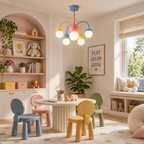 This Clérachic chandelier hangs in a pastel playroom with a round white table, small coloured chairs and an arched shelf alcove behind.