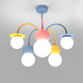 Front view of this Clérachic chandelier lit on a grey backdrop, with a pink centre, curved orange and blue arms and five glowing white globes.