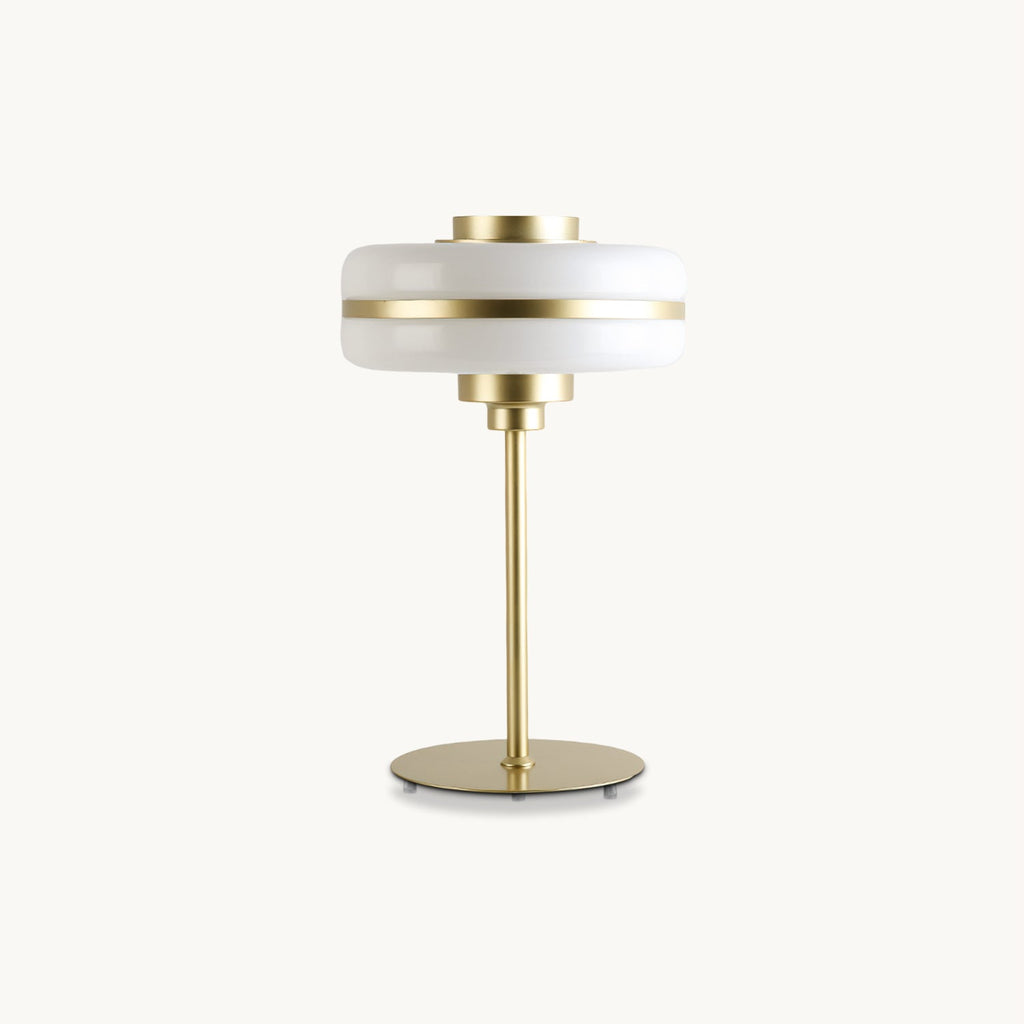 Cut-out view of a Clérachic table lamp with a stacked white glass shade, a brass band and a slim gold stem on a round base, on white.