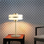 Clérachic table lamp lit on a small side table, its glow cast on a lattice-patterned wall, with an upholstered chair at the edge.