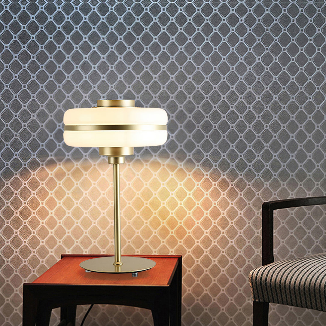 Clérachic table lamp lit on a small side table, its glow cast on a lattice-patterned wall, with an upholstered chair at the edge.