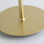 Close view of the flat round gold base and the stem fitting on this Clérachic table lamp.