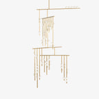 This Clérachic chandelier on a plain white backdrop, with brass rods hung at different heights and small white glass orbs along each one.
