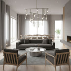 A Clérachic chandelier with brass bars and white orbs over a long dining table in a pale grey open-plan room, with a dark sofa in front.
