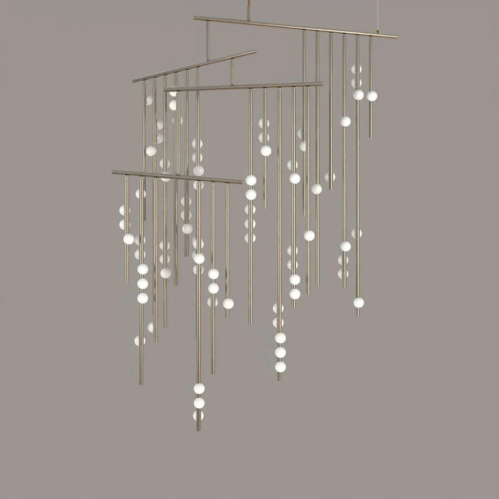 A Clérachic chandelier with many tiers of drop rods in a pale nickel finish, on a taupe backdrop.