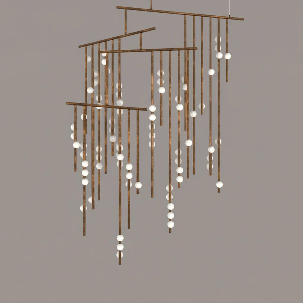 A Clérachic chandelier in antique bronze with many tiers of drop rods and white orbs, on a taupe backdrop.