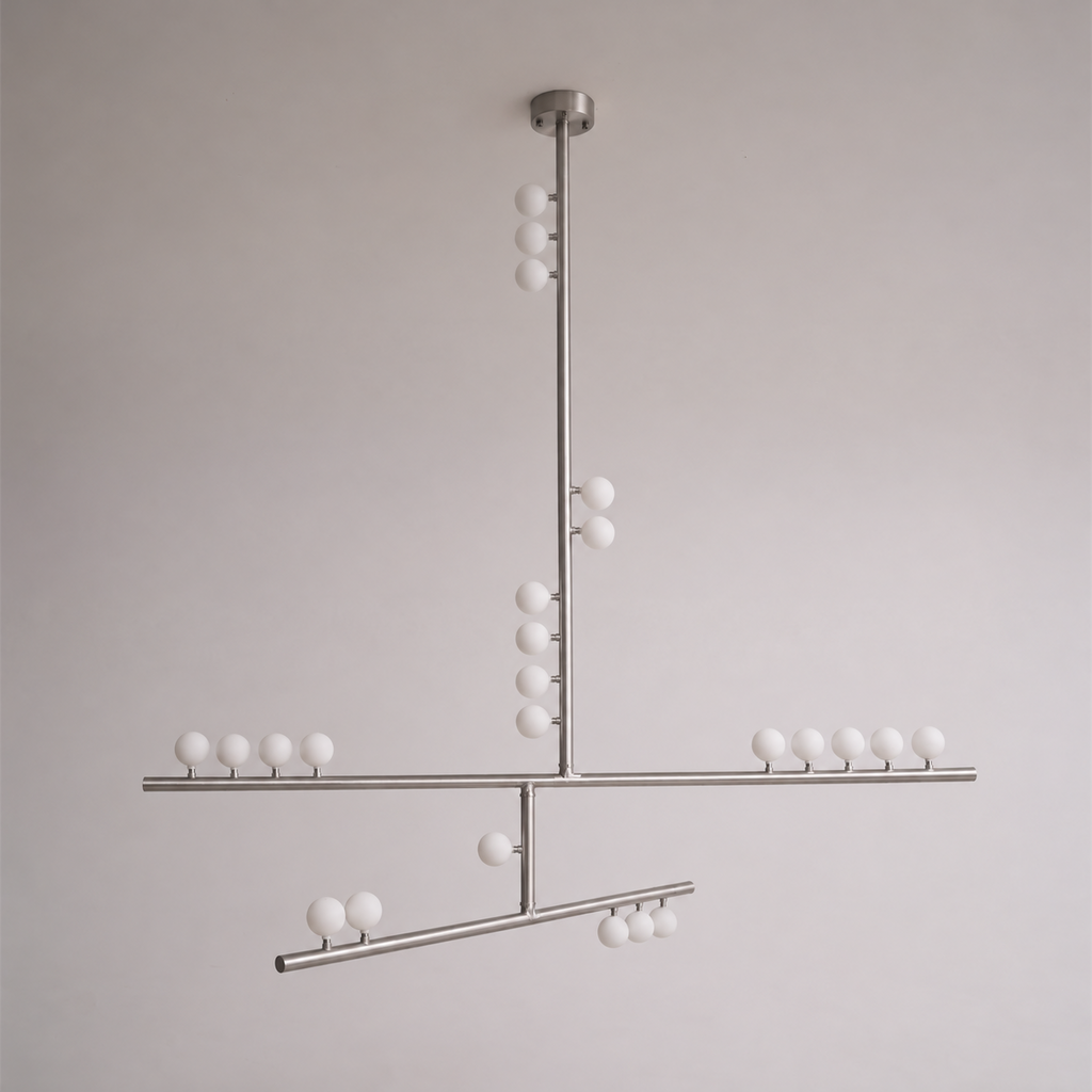 This Clérachic pendant in a nickel-toned finish, with crossed bars and white orbs, on a soft grey wall.