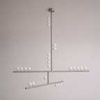 This Clérachic pendant in a nickel-toned finish, with crossed bars and white orbs, on a soft grey wall.