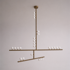 A Clérachic pendant in antique bronze, with a round ceiling plate and crossed bars, on a soft grey wall.