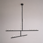 This Clérachic pendant in black with a round ceiling plate and crossed bars of white orbs, against a soft grey wall.