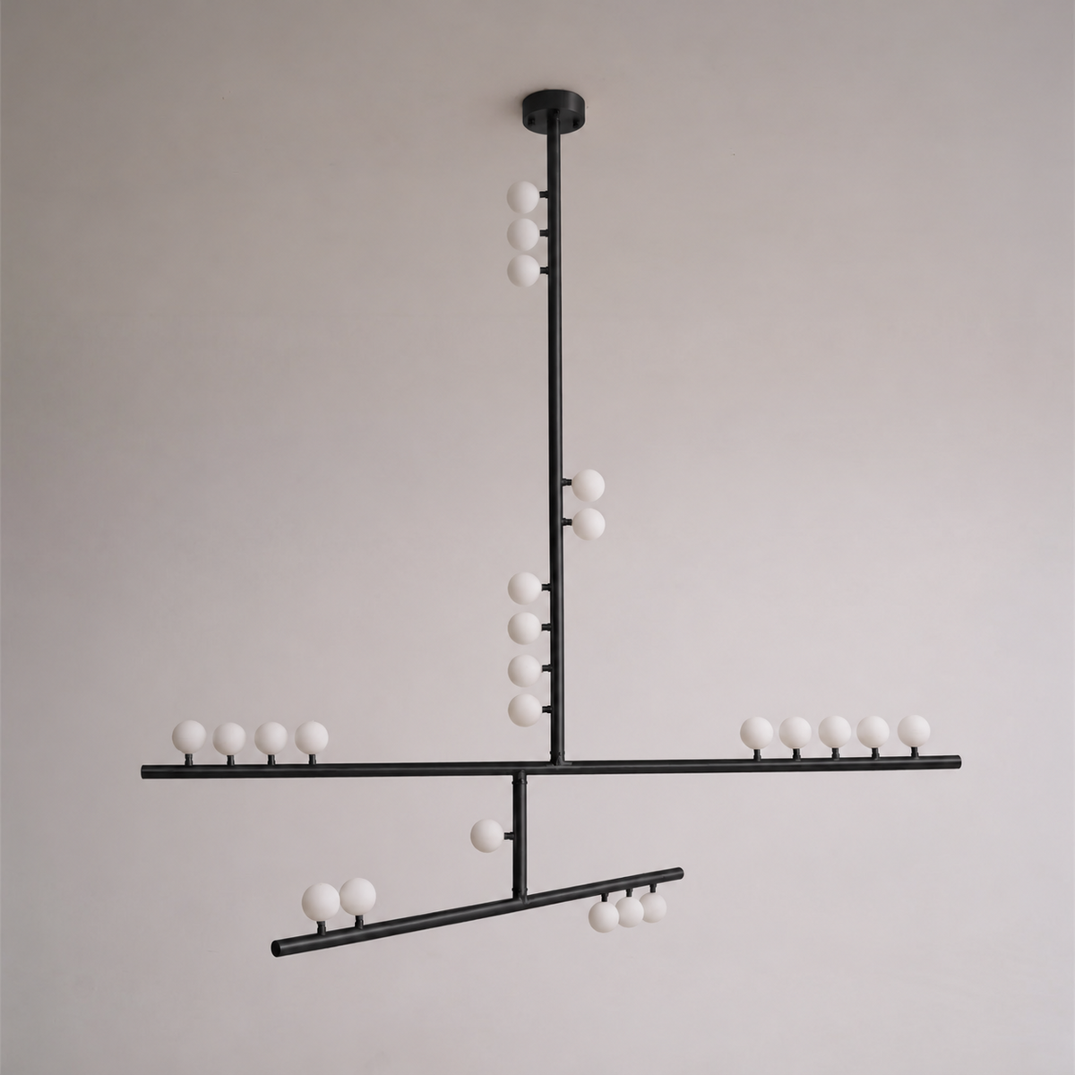 This Clérachic pendant in black with a round ceiling plate and crossed bars of white orbs, against a soft grey wall.