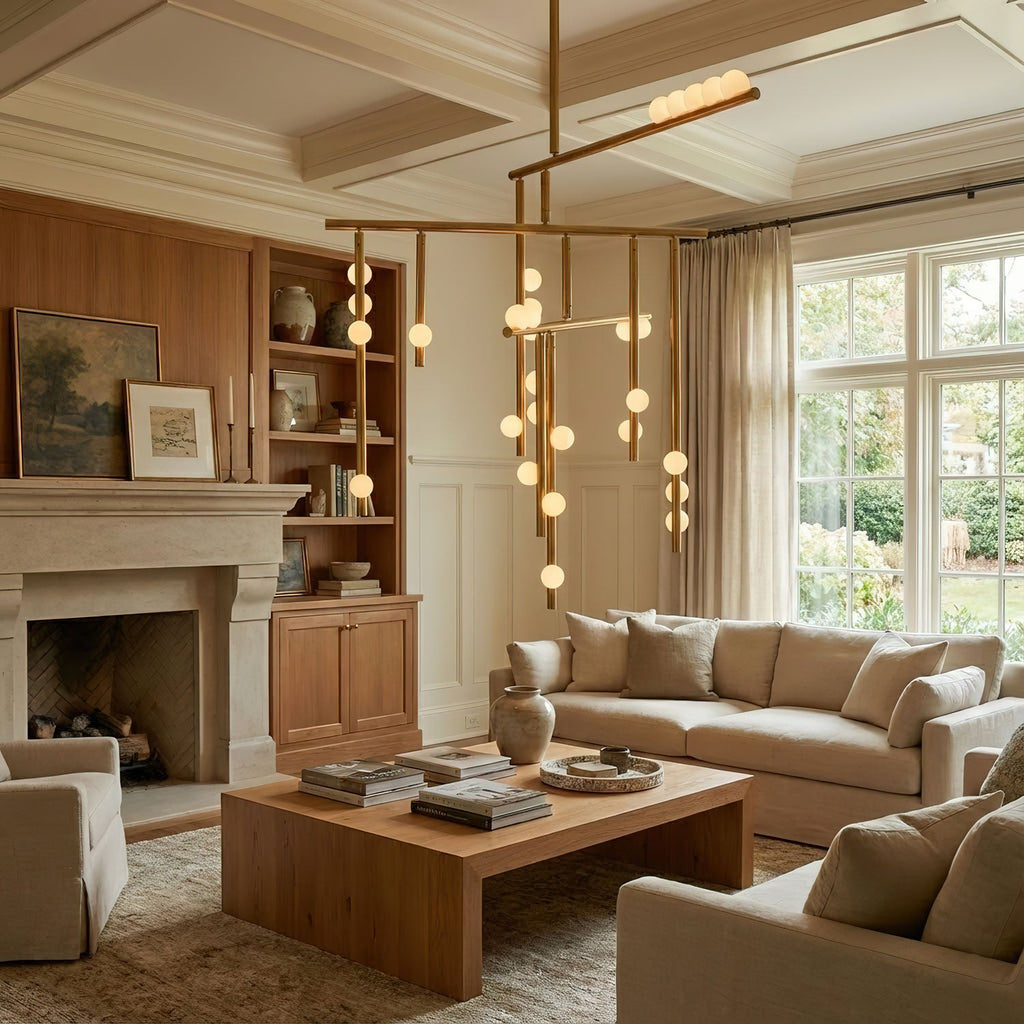 This Clérachic chandelier hangs in a panelled sitting room with a wooden coffee table, its brass bars and white orbs lit warm.