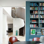 A Clérachic pendant seen from a landing in a white hallway with a teal bookcase, its brass rod and orbs hanging down the stairwell.