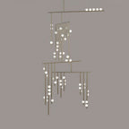 This Clérachic chandelier in a pale nickel-toned finish, on a taupe backdrop, with white orbs along each rod.