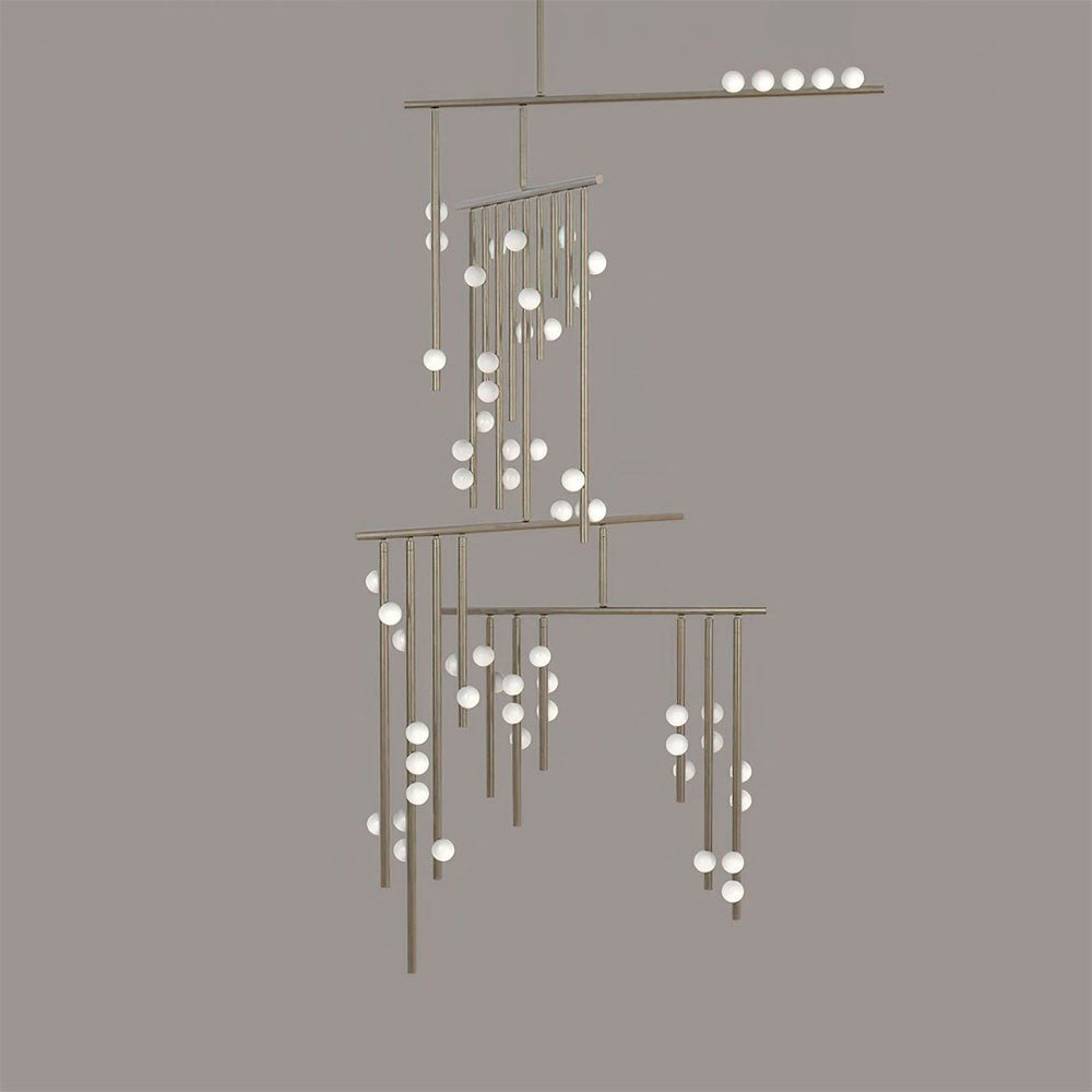 This Clérachic chandelier in a pale nickel-toned finish, on a taupe backdrop, with white orbs along each rod.