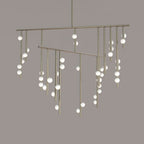 Close view of the long brass rods and scattered white orbs on this Clérachic chandelier, against a taupe backdrop.