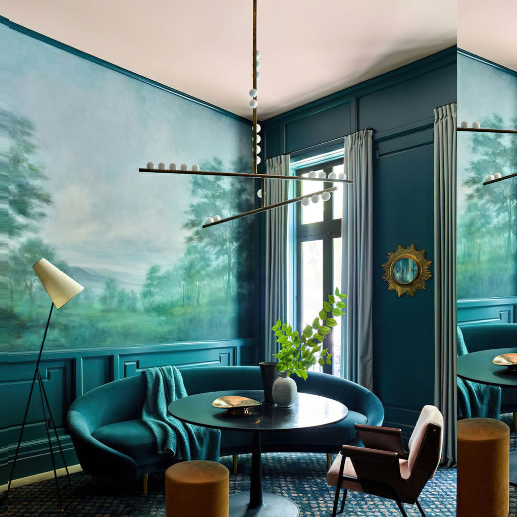 A long Clérachic linear pendant hangs in a deep teal room with a mural and a round black table, its orbs lit.
