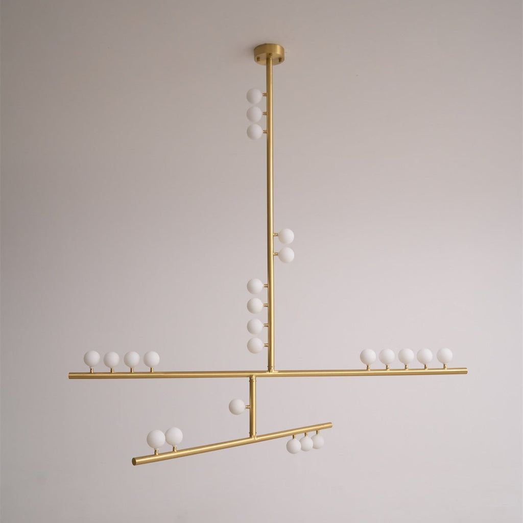 A brass Clérachic pendant with a round ceiling plate and white orbs along its bars, unlit on a pale grey backdrop.