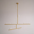 A brass Clérachic pendant with a round ceiling plate and white orbs along its bars, unlit on a pale grey backdrop.