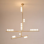 The same Clérachic pendant lit warm, with its brass rod, round canopy and white orbs glowing on a peach-toned backdrop.