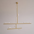 This Clérachic pendant in brass, unlit, hung against a soft grey wall with a clear view of its three bar tiers.