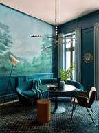 This Clérachic pendant hangs in a teal room with a landscape mural and a round black table, a floor lamp to the left.