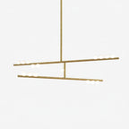 This Clérachic two-bar pendant in brass with white orbs along the bars, on a pale backdrop.