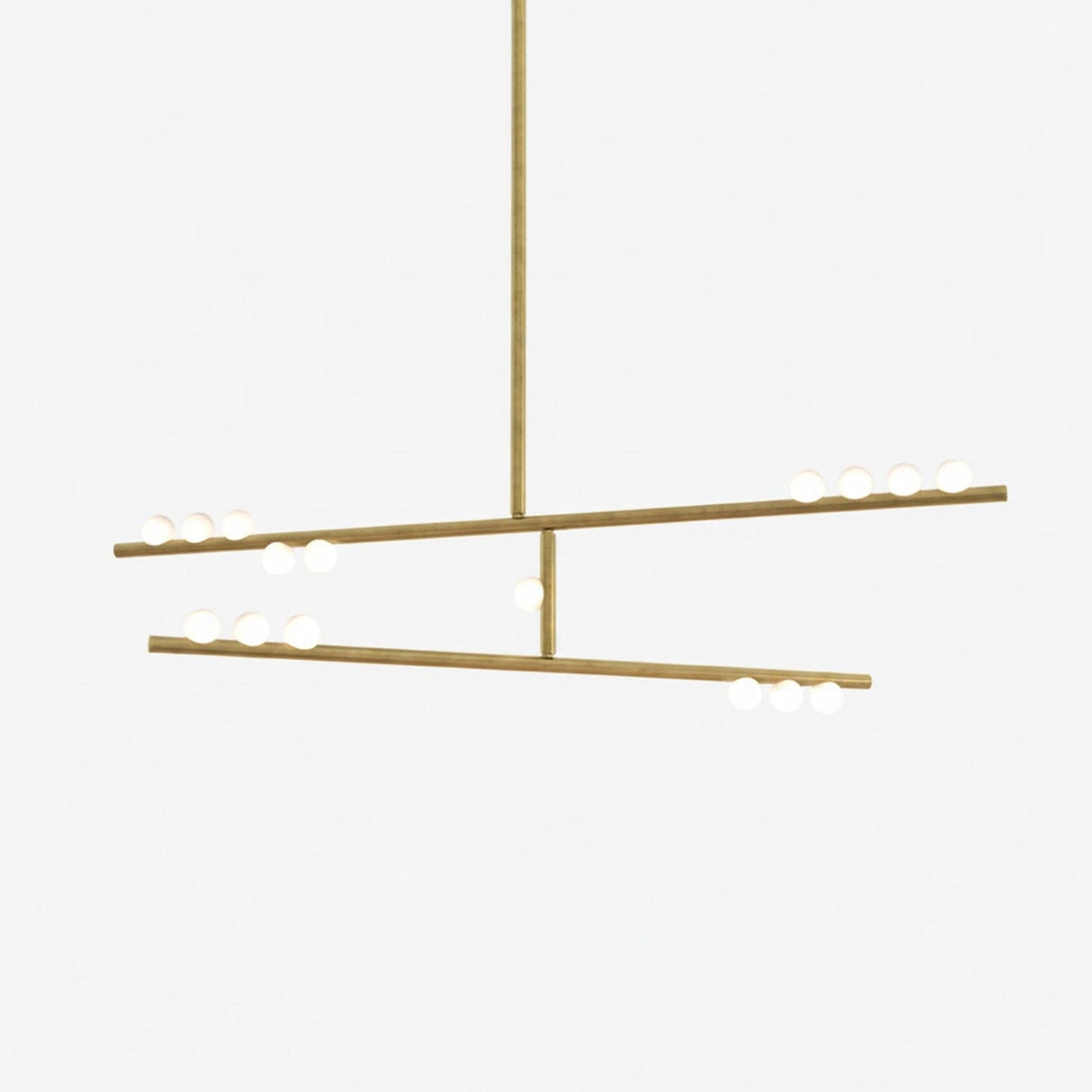 This Clérachic two-bar pendant in brass with white orbs along the bars, on a pale backdrop.