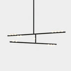 A black Clérachic two-bar pendant with white orbs along each bar, on a pale backdrop.