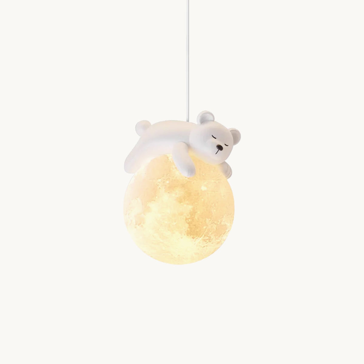 A small white bear lies asleep on a glowing moon-textured globe, this Clérachic pendant light hanging on a plain white backdrop.