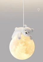 A white bear dozes on top of the cratered, glowing globe of this Clérachic pendant, set on a soft grey backdrop.