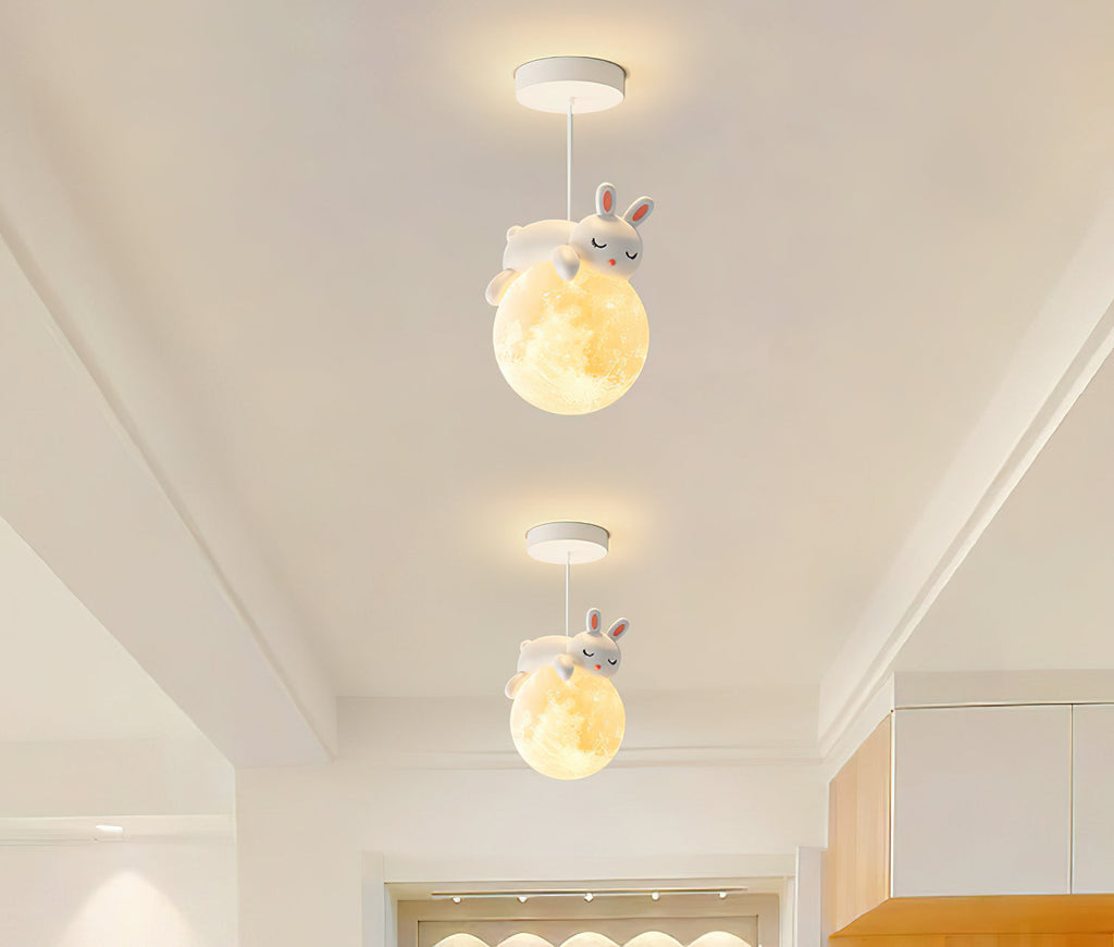 Two Clérachic pendants with rabbit figures on glowing globes hang one behind the other in a narrow, bright corridor.