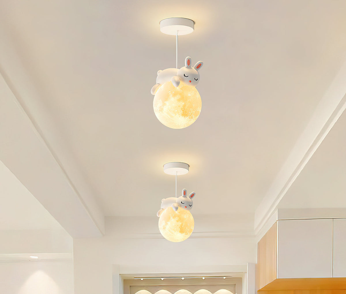 Two Clérachic pendants with rabbit figures on glowing globes hang one behind the other in a narrow, bright corridor.