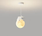 A Clérachic bear pendant hangs from a white round ceiling plate, its glowing globe lit warm against a grey wall.