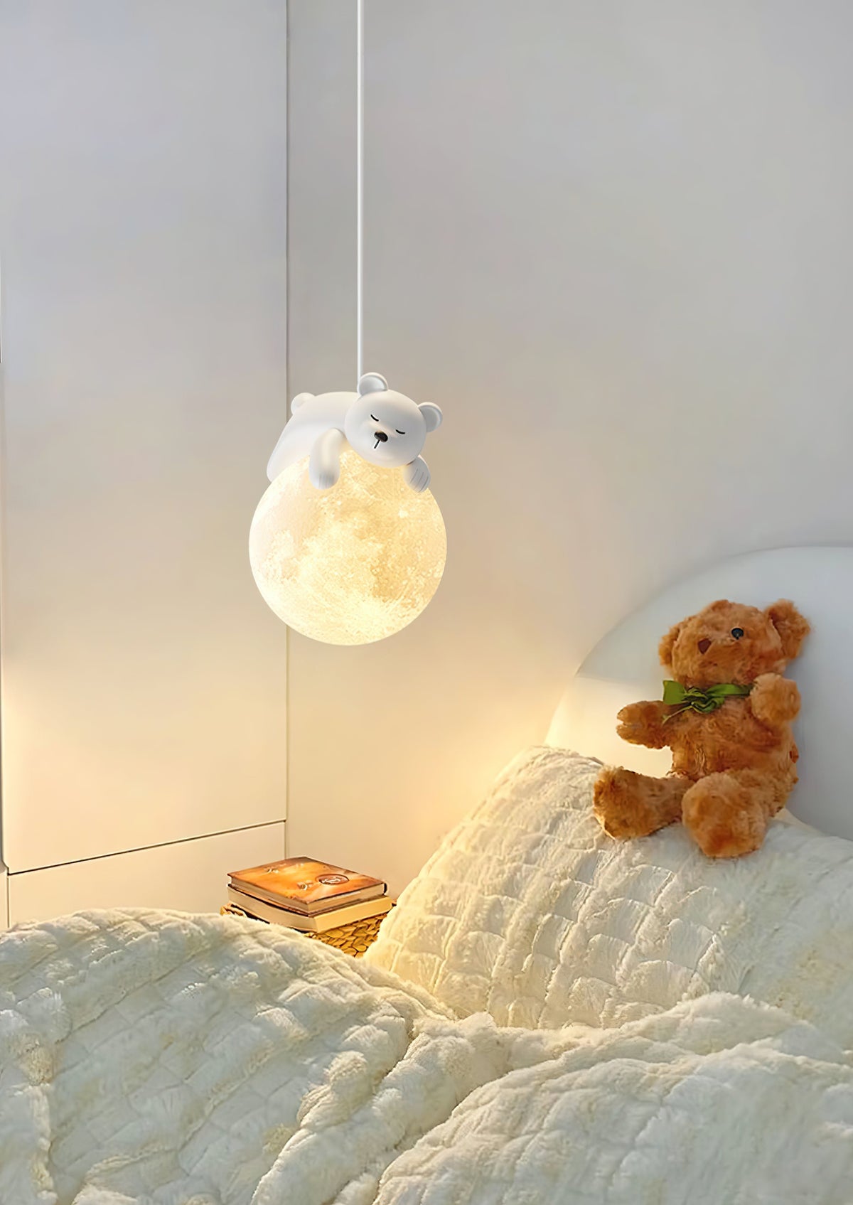 A Clérachic pendant with a bear on a moon globe glows above a bed with textured cream bedding and a teddy bear.