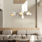 A Clérachic pendant with four lit openings, hanging in sunlight in front of a cream wall and a modular boucle sofa.
