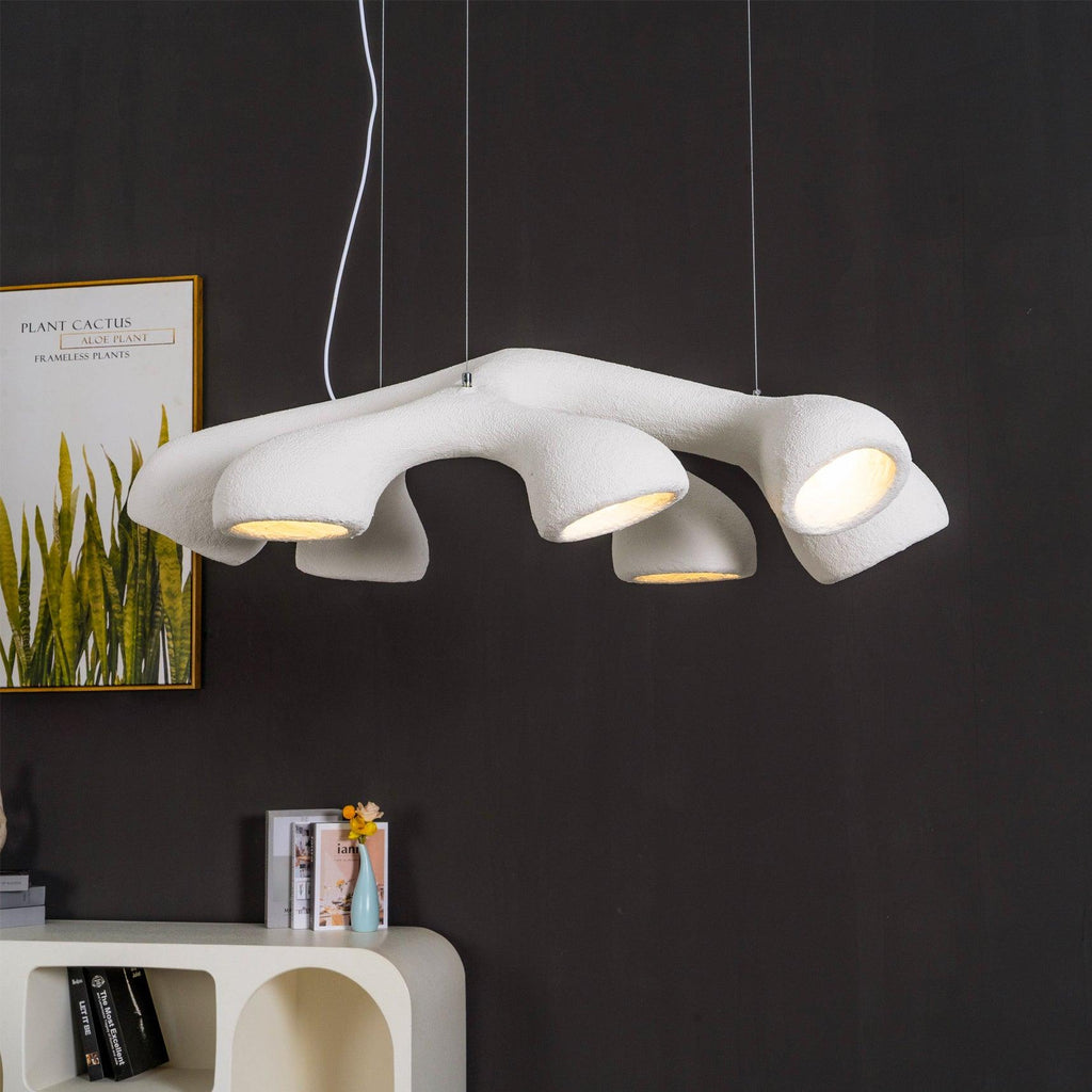 Angled view of a Clérachic pendant against a black wall, its white organic form spreading into several lit openings.