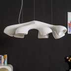 Wide, low angle on a Clérachic pendant against a black wall, showing the rough white surface and the folds between its arms.