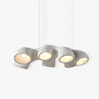 A long four-opening Clérachic pendant on a pale backdrop, hanging from three thin cables with each bulb lit.