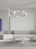 A Clérachic pendant with branching white arms above a pale sectional sofa and a round table, a blue panel at the left.