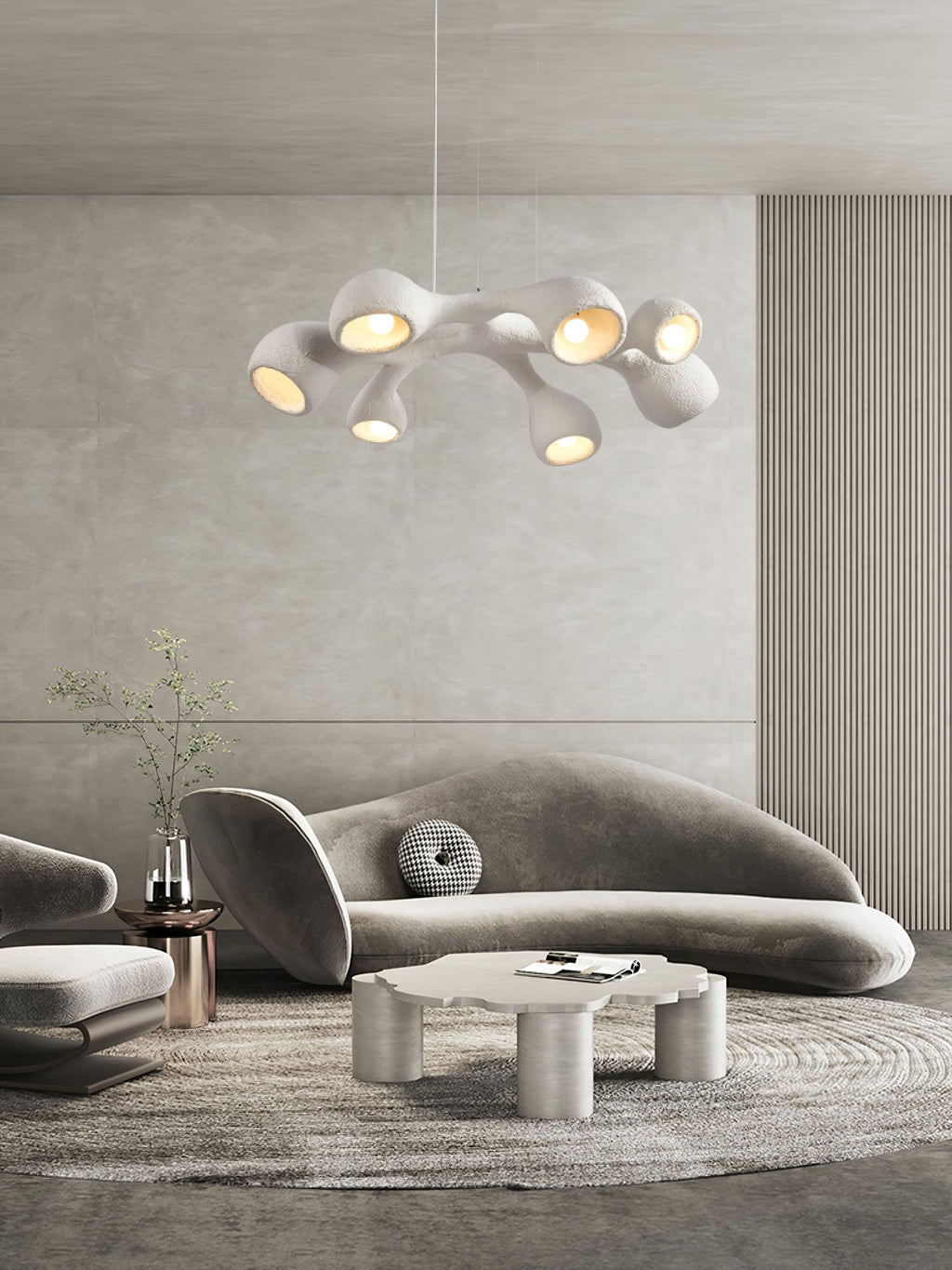 A Clérachic pendant high above a curved grey sofa and a cloud-shaped coffee table, in a room with a ribbed wall panel.
