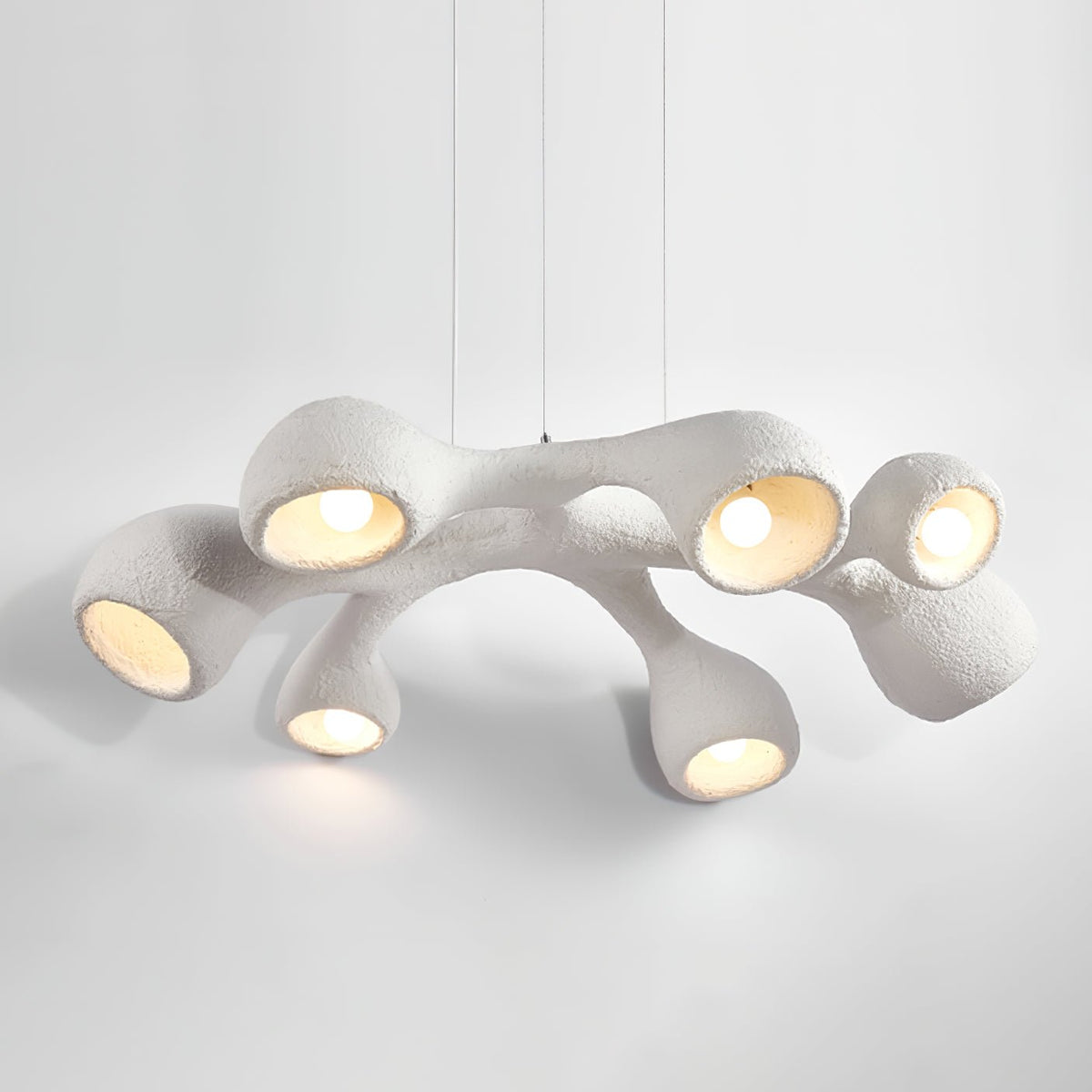 Clérachic pendant on a pale grey backdrop, its branching white arms lit from inside and casting a soft glow below.