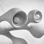 Close view of two bulbs sitting inside the openings of this Clérachic pendant, with the uneven plaster-like white surface around them.